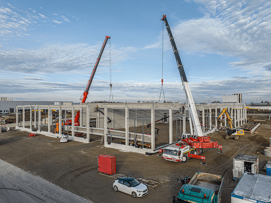 Schwere Betonquerbinder mit 33m Länge werden mit schwerem Gerät in Position gebracht.